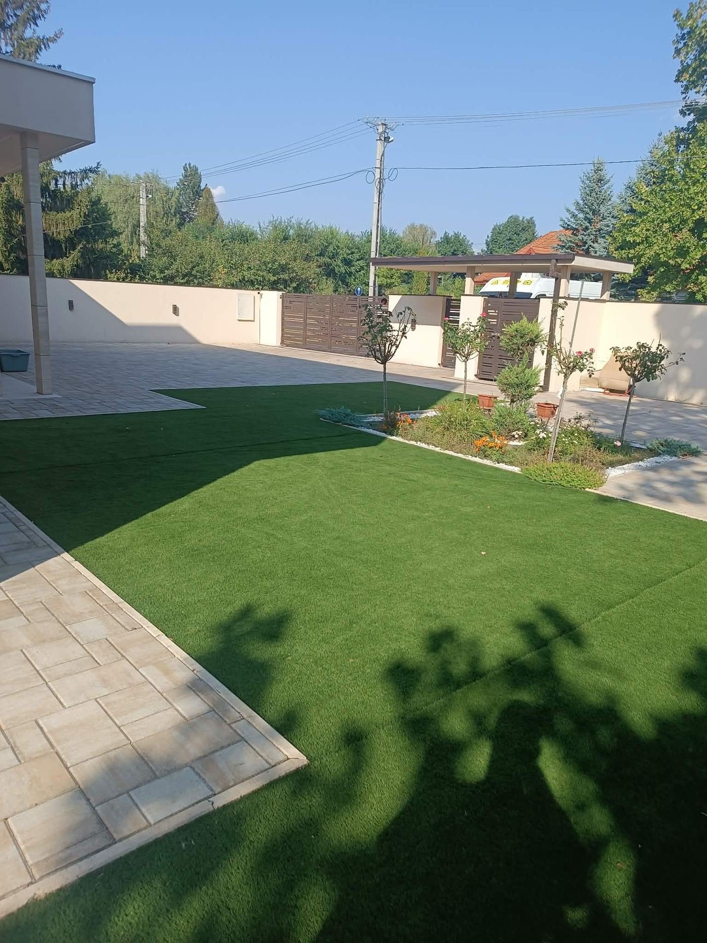 Modern kert műfűvel, térkövezett bejáróval